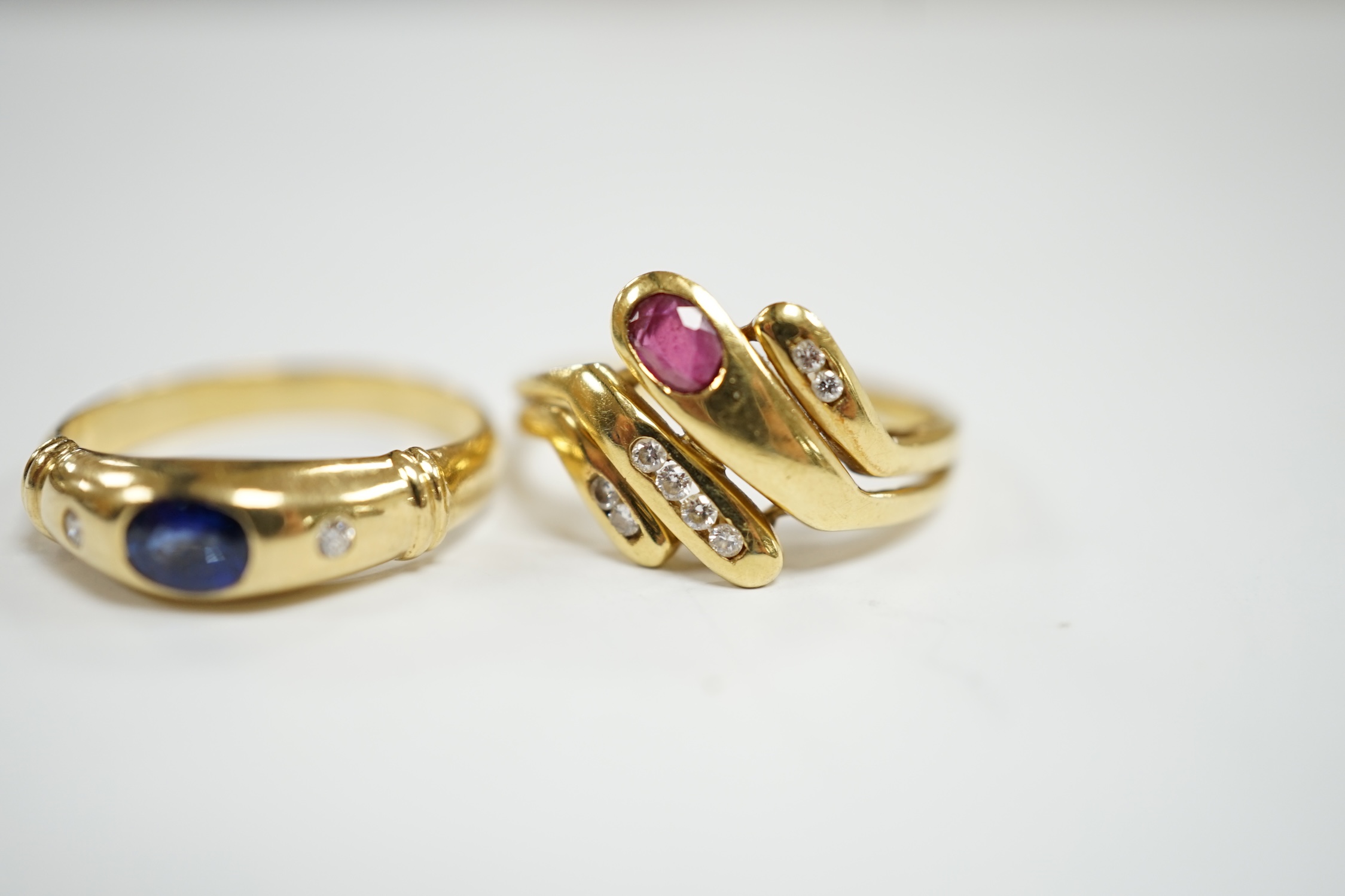 A modern 750 yellow metal and gypsy set single stone sapphire and two stone diamond set ring, size N, together with an Italian 750 yellow metal, ruby and diamond cluster set dress ring, size , gross weight 6.8 grams.
